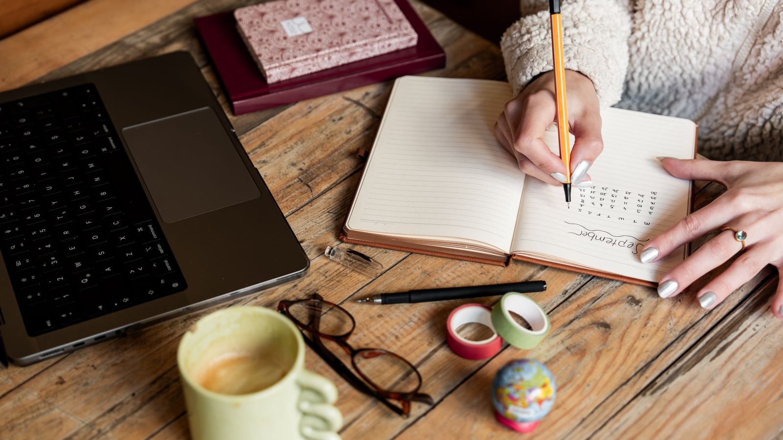 Newsletter planning on a wooden desk with notepad, laptop, and coffee