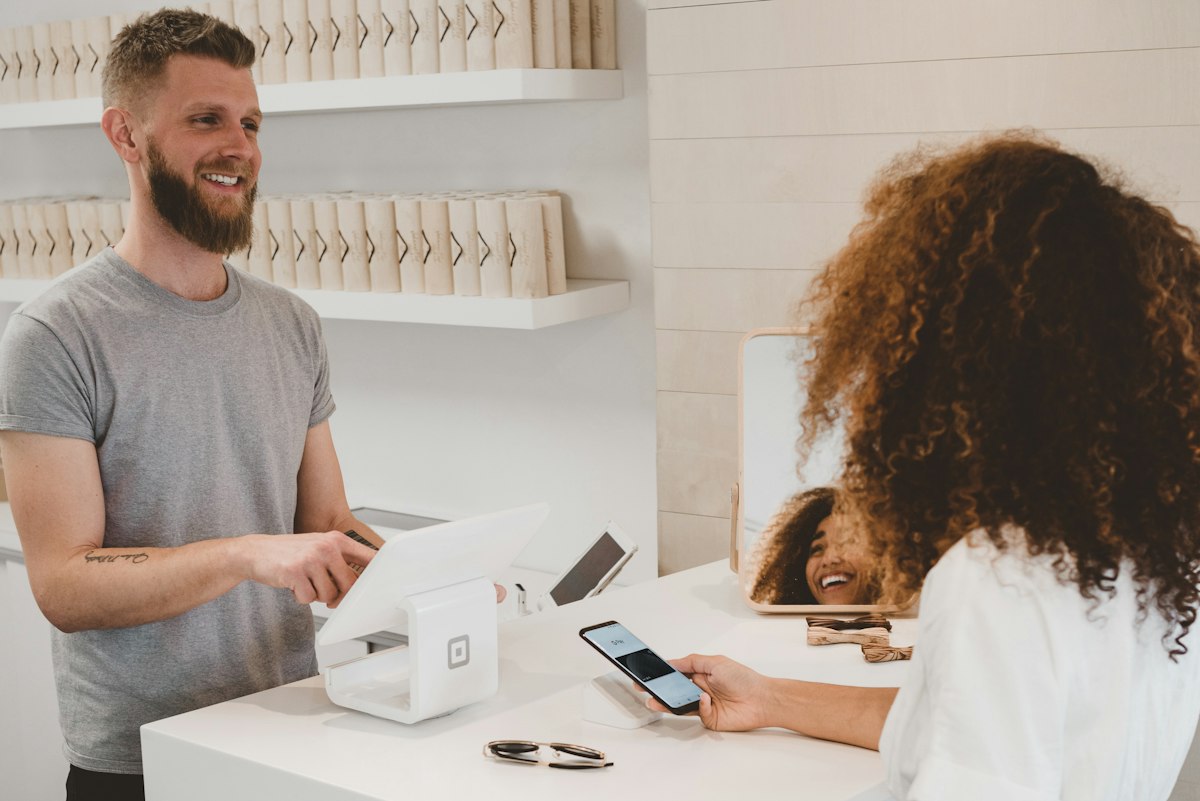 Card payment at a checkout terminal, representing fees when selling digital products