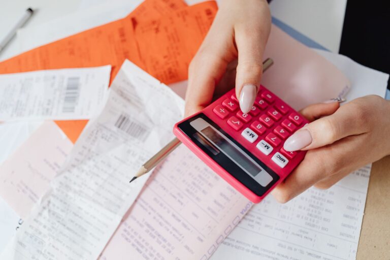 Hands with a calculator sorting receipts and invoices at a small business desk