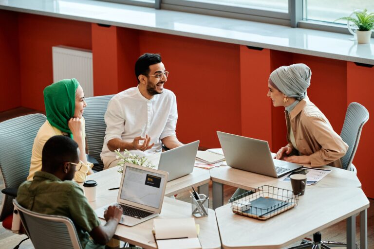 Group of diverse coworkers having a collaborative discussion together with laptops